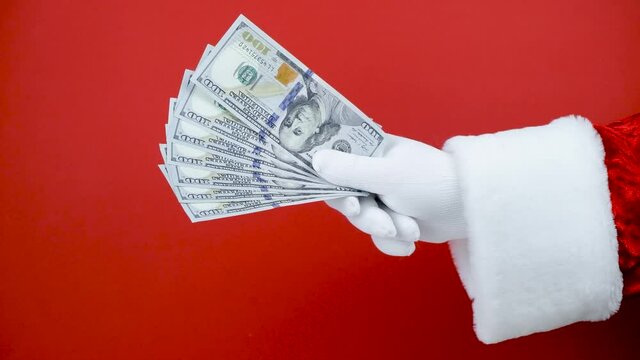 Santa Claus hand holding money on red background. Hand with cash.