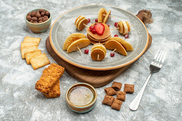 Buttermilk fruit pancakes on wooden cutting board with cookies biscuits honey on blue background