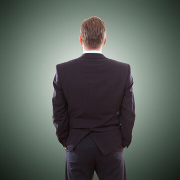 business man in suit from the back isolated over dark background