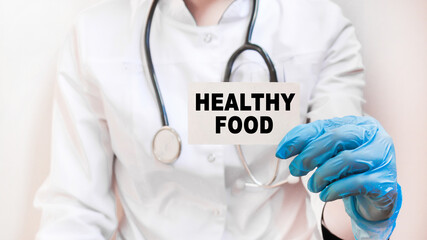 The doctor's blue - gloved hands show the word HEALTHY FOOD - . a gloved hand on a white background. Medical concept. the medicine