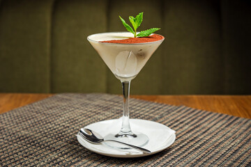 A classic tiramisu dessert in a martini glass, garnished with mint