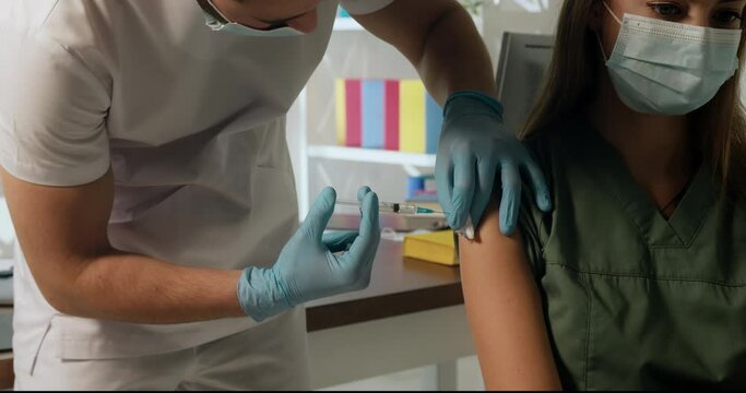 Vaccination of healthcare workers. Male doctor injecting a vaccine into female nurse's shoulder. Mass immunization. Close up shot.