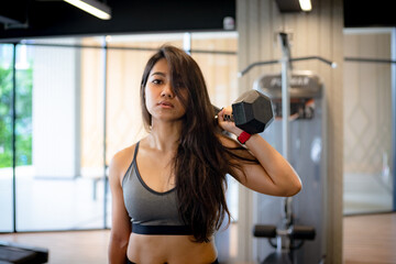Fototapeta premium Young slim woman doing exercises with dumbbell in gym