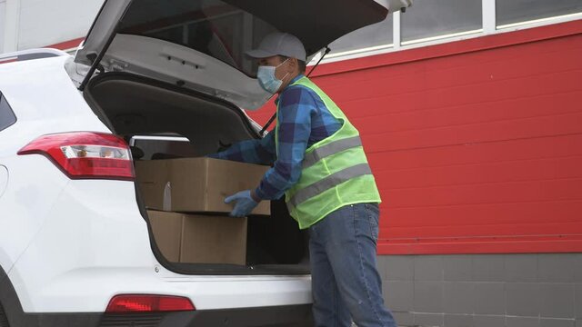 Volunteer wearing a mask and gloves delivers parcels. Online shopping during the covid-19 coronavirus pandemic. Contactless delivery of goods by courier service. Delivery during the coronavirus period