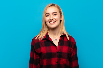 young blonde woman with a big, friendly, carefree smile, looking positive, relaxed and happy,...