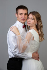 Classic vertical portrait of the bride and groom on a gray background.