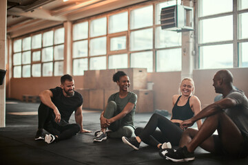 Laughing group of diverse friends talking on a gym floor