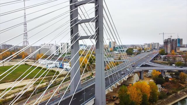 Ciurel passage, bridge over a river with moving cars, construction works, field and TV tower near it. Residential buildings on the background. View from the drone. Bucharest, Romania