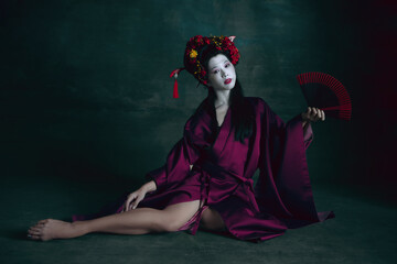 Passioned. Young japanese woman as geisha isolated on dark green background. Retro style,...