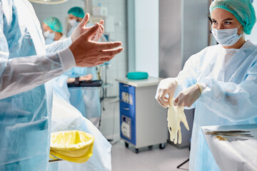 close doctors team help wearing medical uniform to each other, prepare for operation.hospital personnel wearing face mask, gloves and robe. coronavirus outbreak