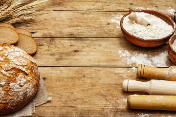 Fresh bread with wheat ears and a bowls of flour and grain, rolling pins