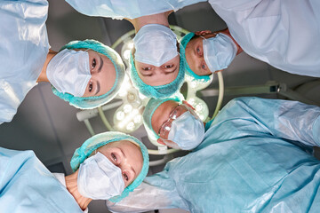 view from below on friendly team of confident concentrated caucasian surgeons in operating room...
