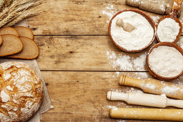 Fresh bread with wheat ears and a bowls of flour and grain, rolling pins