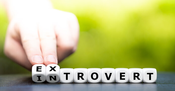 Hand turns dice and changes the word introvert to extrovert.