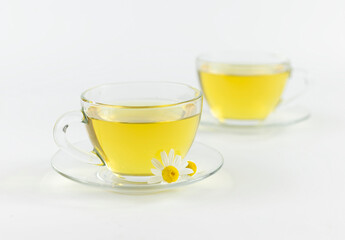 glass cups with chamomile tea on a white background and flower of daisies.