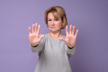 Middle age woman doing stop sing with palm of the hand. Warning expression with negative and...