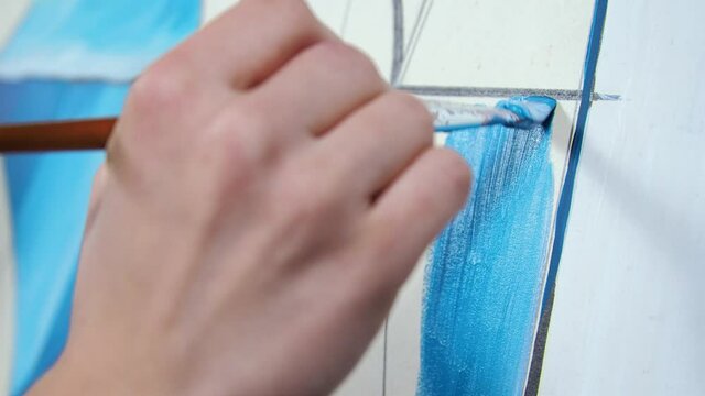Young blond woman artist paints a picture in blue colors. Macro Palette