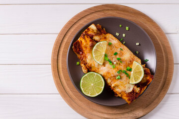 Mexican enchiladas with chicken, cheese, tomatoes and peppers. Mexican food. Latin American cuisine. On a white, wooden background