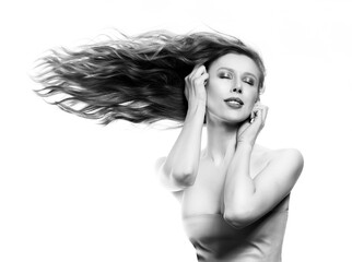 A beautiful girl with large breasts and naked shoulders sensually touches her face with hands, while her long hair flutters horizontally to the side. Isolated on white. Advertising, monochrome design