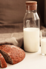 Milk and crusty homemade bread loaf with flax seeds on beige and white background. Natural products concept