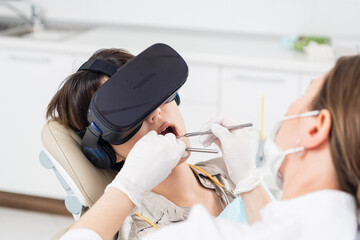 The dentist is working on the treatment of cavities, while her patient is wearing the VR glasses.