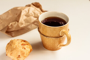 Cup of black tea, cheese roll, a brown kraft paper bag on white background. Isolated.  Snack time. Stock photo