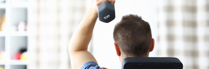 Close-up of male lifting dumbbells with one hand at home. Fit and strong body on quarantine period. Gym time indoors. Health and active lifestyle concept