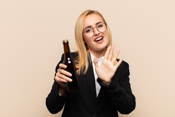 young blonde woman feeling terrified, backing off and screaming in horror and panic, reacting to a...