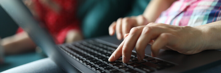 Close-up of persons hand working on laptop sitting on cozy sofa. Young female typing on grey modern device. Freelancer on quarantine period. Technology and remote job from home concept