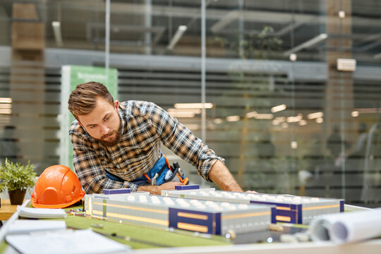 confident architect man working in office with drawings and building layout, small building model, work on project