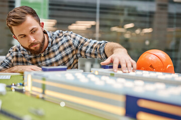 confident architect man working in office with drawings and building layout, small building model,...