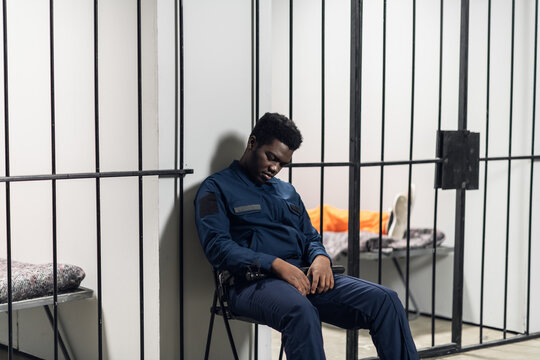 A prison warden guards cells with prisoners sentenced to life in orange prison uniforms