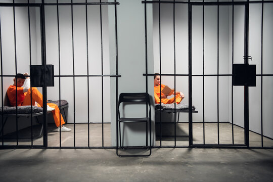 Prisoners in their cells are bored before lights out in prison. Read books. Symmetrical composition. Copy space.