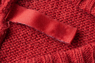 Blank laundry care clothes label on red knitted fabric texture background