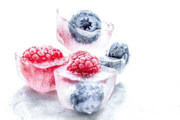 Ice cubes with frozen berries on white background