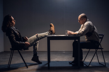 The suspect in the smuggling case is sitting relaxed and with his feet up on the table in the interrogation room with the investigator