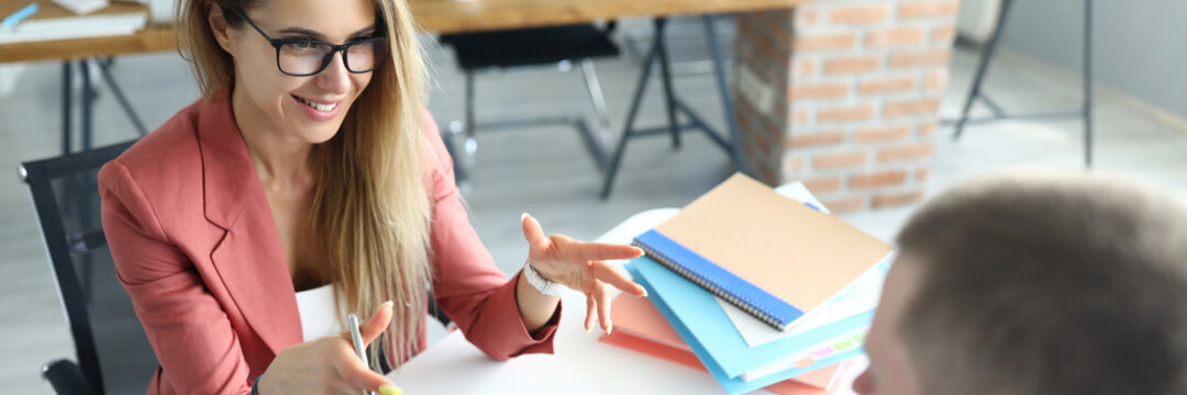 Portrait of two people involved in talk. Man and woman discuss working situation. Modern tablet with black screen. Business papers on desk. Smart qualified workers in office. Job concept