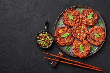 Tod Mun Pla or Thai Fish Cakes on black plate on dark slate table top. Traditional Thailand cuisine dish. Asian food and meal. Copy space. Top view