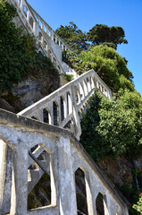 Old staircase on Alcatraz Island in San Francisco Bay, plants all around, blue sky background