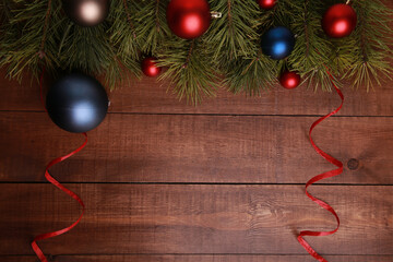 Christmas pine tree branches, red and blue balls and streamer on brown wooden background. Xmas or New Year celebration, decoration, party concept. Top view, copy space