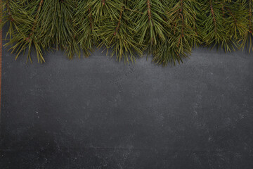 Christmas pine tree branches on dark grey background. Xmas or New Year celebration concept. Top view, copy space, border, template for greeting cards and postcards.