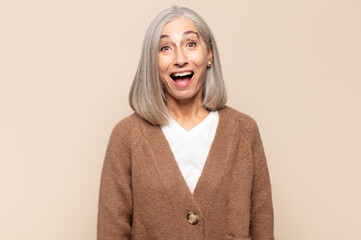 middle age woman looking happy and pleasantly surprised, excited with a fascinated and shocked...