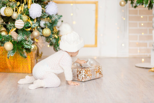 New Year's photo of the baby near the Christmas tree with a gift