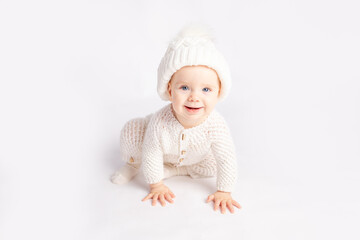 baby crawls in a warm suit and hat on a white isolated background, space for text