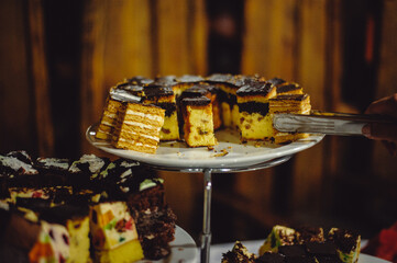 a human hand takes a cake on a buffet table. Candy Bar, Cake, Cheesecake. Film noise