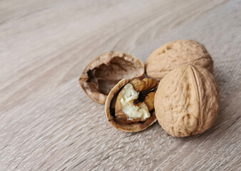Two whole walnuts and one cracked walnut on a wooden table