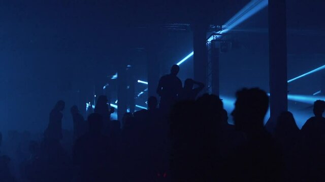 Big crowd of young people dancing at large music show event in nightclub