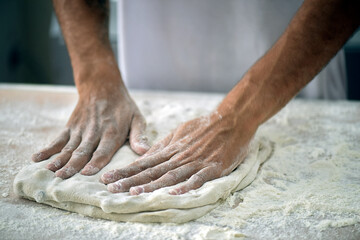 Baker preparing dough of bread for baking at the bakery