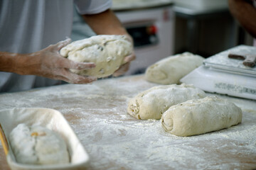 Fototapeta na wymiar Baker preparing dough of bread for baking at the bakery