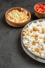 Top view of seasoned split peas and rice for dinner and sauerkraut and tomato on dark background
